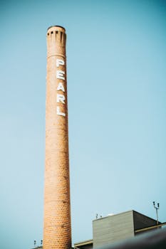 A towering industrial chimney labeled 'PEARL' against a clear sky in San Antonio. by Fabio Lima