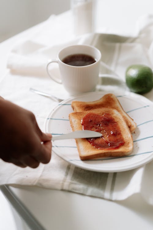 A Person Spreading Jam on Toast