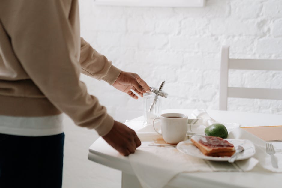 Assisted living facilities near me - A person preparing a breakfast table with coffee, jam toast, and avocado indoors.