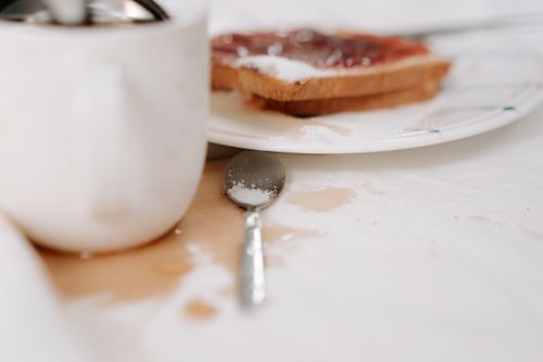 Free Close-up of a messy breakfast table with coffee spill, toast, and sugar. Stock Photo