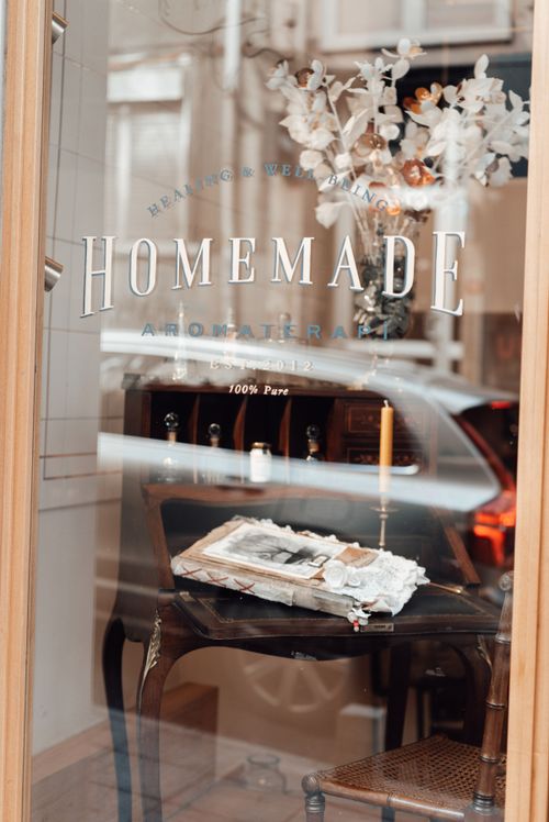 Free Elegant shop window display with candle, flowers, and vintage decor, reflecting a cozy atmosphere. Stock Photo