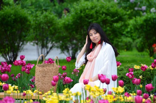 Free Woman Sitting on a Bench on Flower Garden Stock Photo