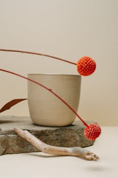 Elegant still life featuring Craspedia in a ceramic pot with a simple, modern aesthetic on stone.
