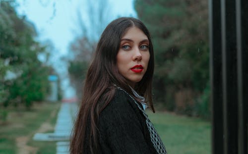 Serious woman with makeup standing on pathway in park