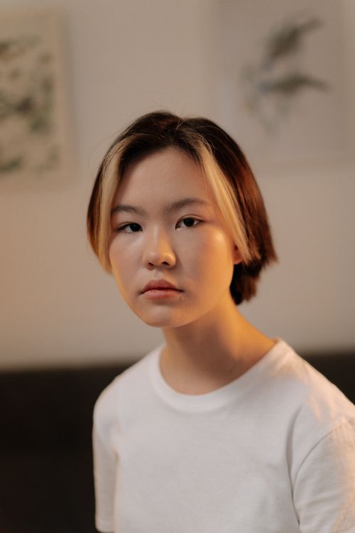 Free Portrait of a young woman with short hair wearing a white shirt, shot indoors with a soft, neutral tone. Stock Photo