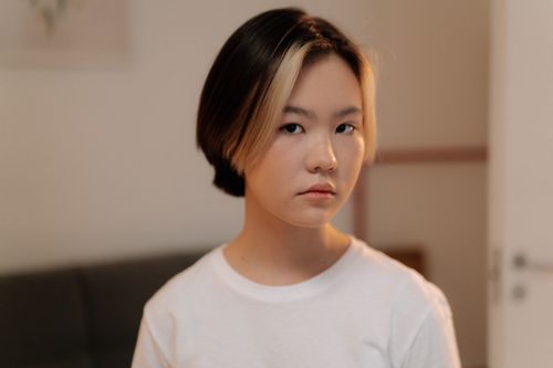 Free Portrait of a young woman with short hair in a white shirt, indoors. Stock Photo