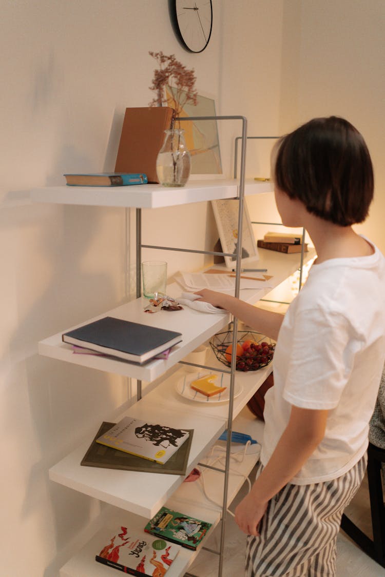 A Person Wiping A Shelf With A Cloth