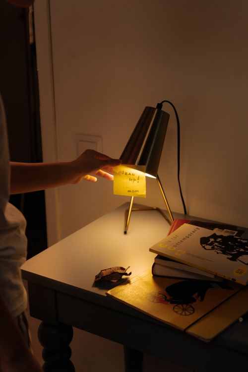 Free A warm bedside lamp illuminating books and a sticky note in a cozy indoor setting. Stock Photo