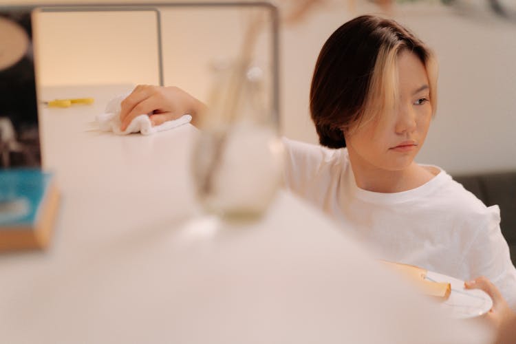 A Woman Wiping A Shelf With A Cloth