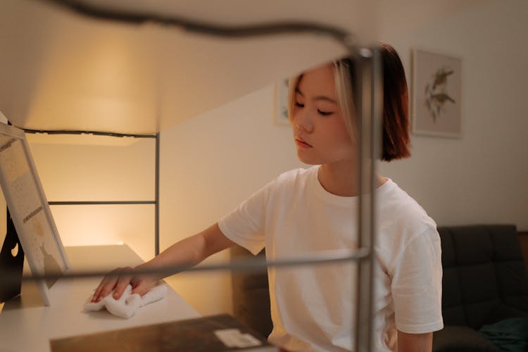 A Woman Wiping A Shelf With A Cloth