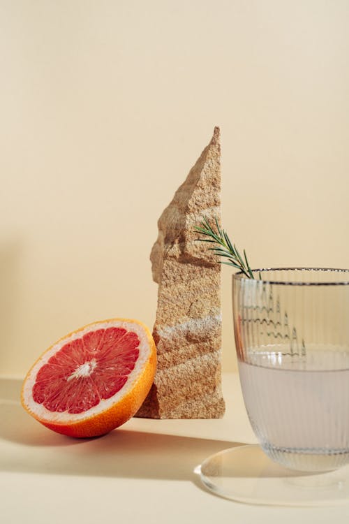 Sliced Grapefruit Beside Clear Drinking Glass With Water