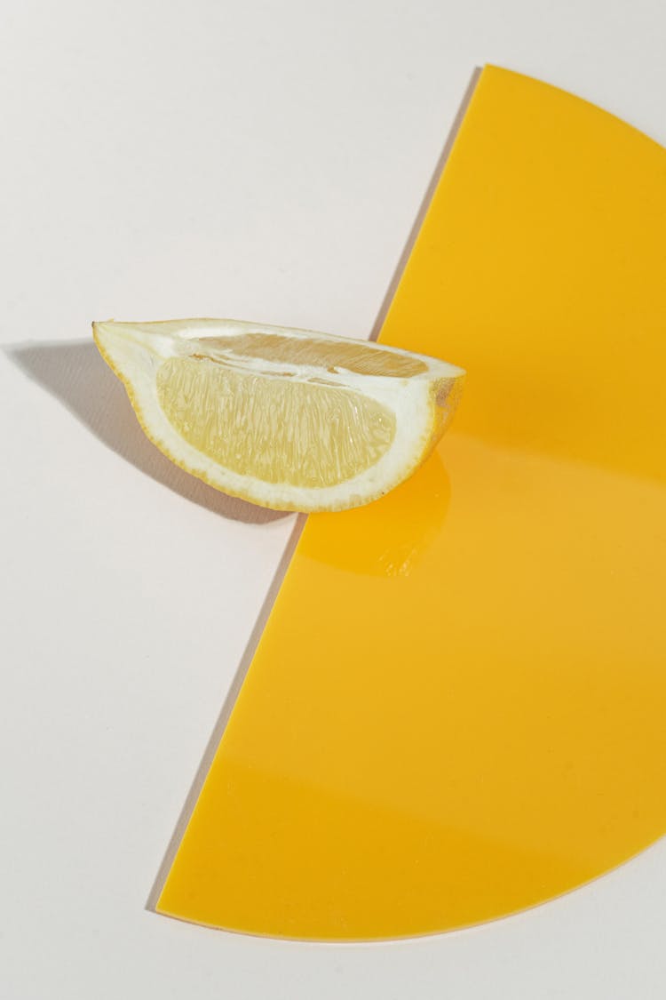 Yellow Sliced Lemon Beside Yellow Paper