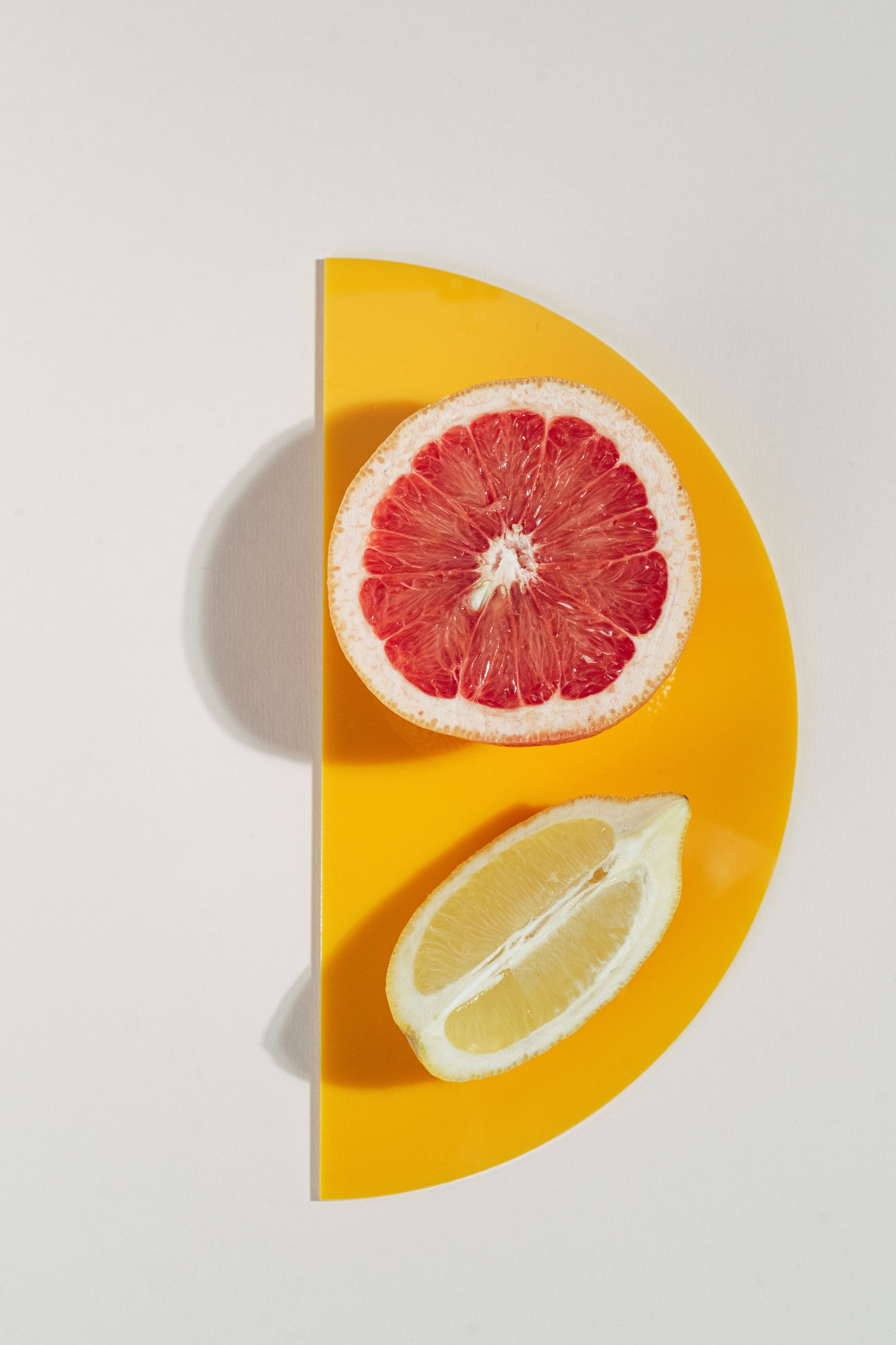 Colorful grapefruit and lemon half on a vibrant yellow plate creating a modern still life.