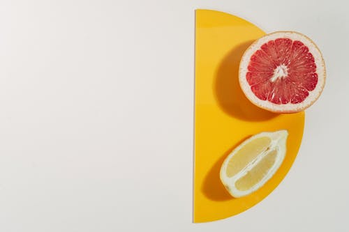 Halved Red Grapefruit and a Quarter of Lemon on a Yellow Semicircular Tray