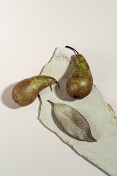 High-angle still life of pears with a dried leaf on a textured background.