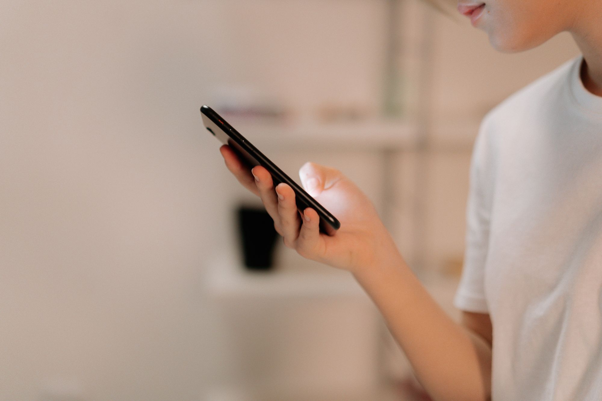 Close-up of a person using a smartphone indoors, focusing on hand and device.