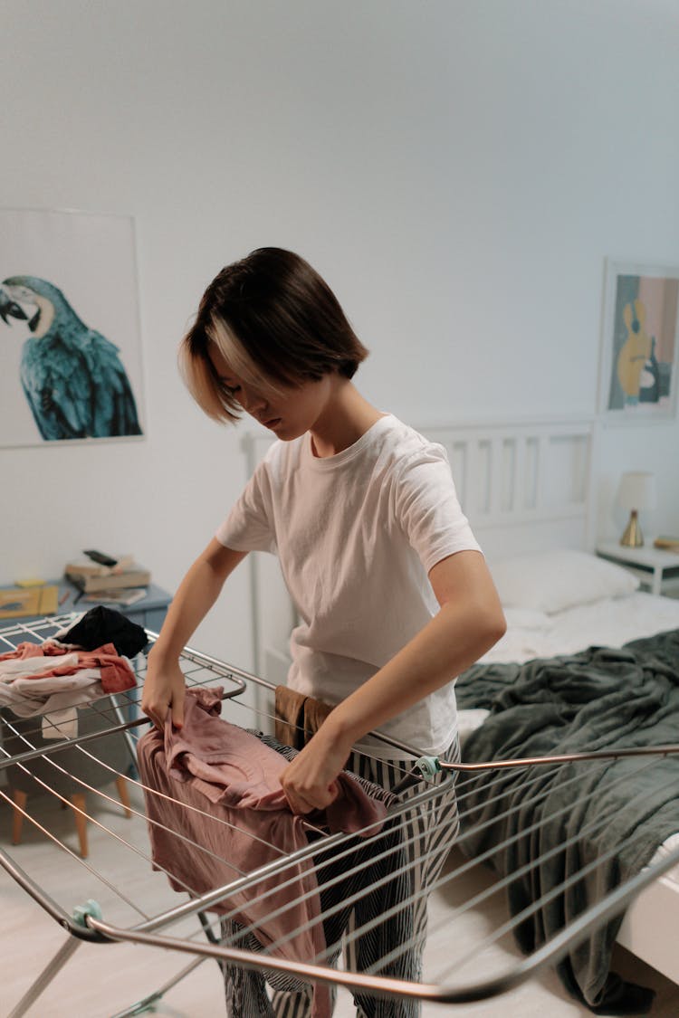 A Woman In White Shirt Folding Clothes