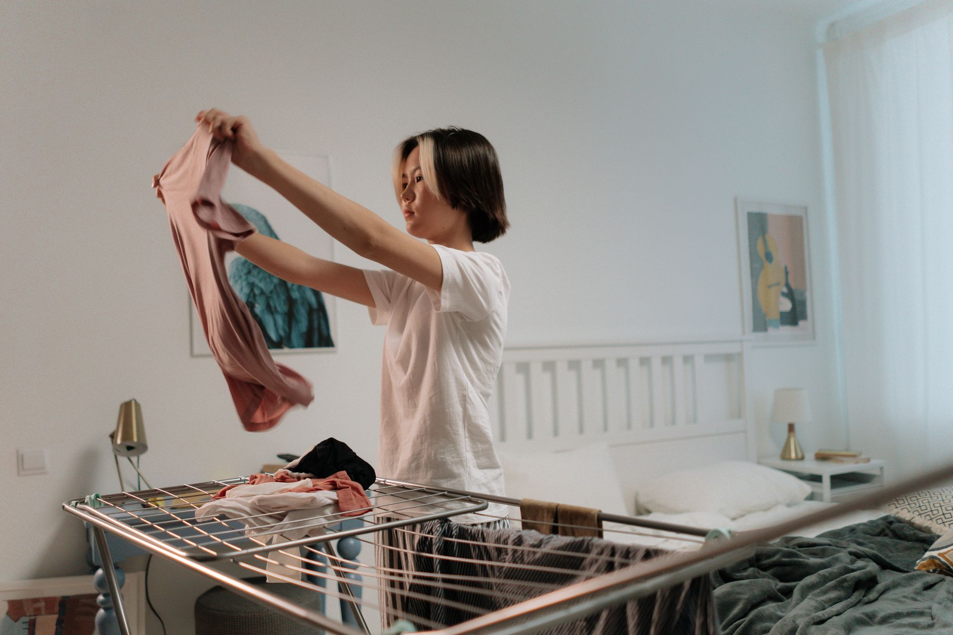 Asian woman folding clothes at home in a tidy bedroom. Lifestyle concept.