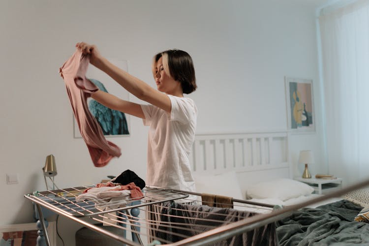 A Woman In White Shirt Folding Clothes