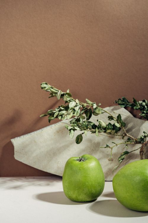 Free Close-up of fresh green apples with lush foliage on a neutral background, perfect for food photography. Stock Photo
