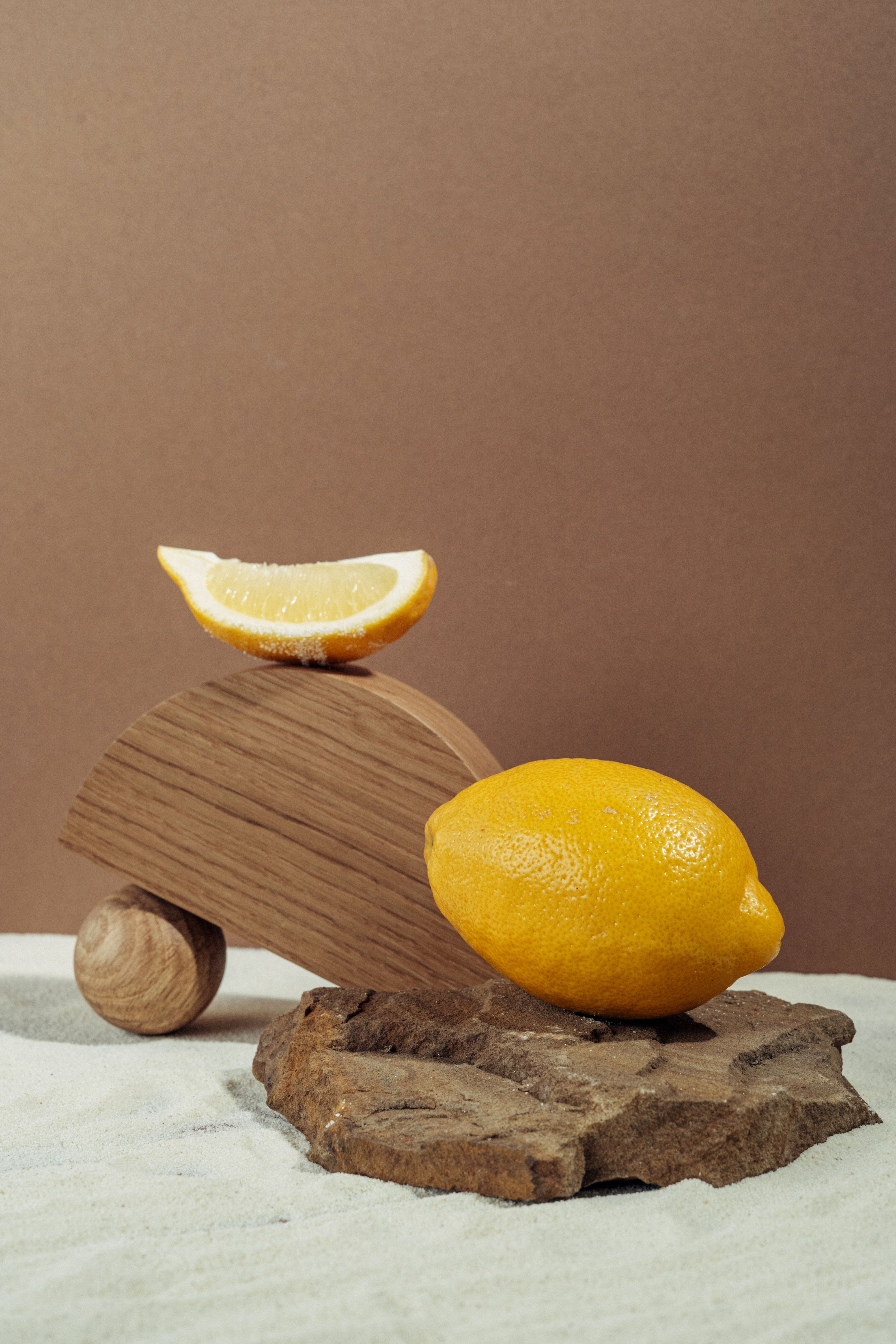 Artistic still life of a lemon and wooden shapes on textured surface, perfect for food photography.