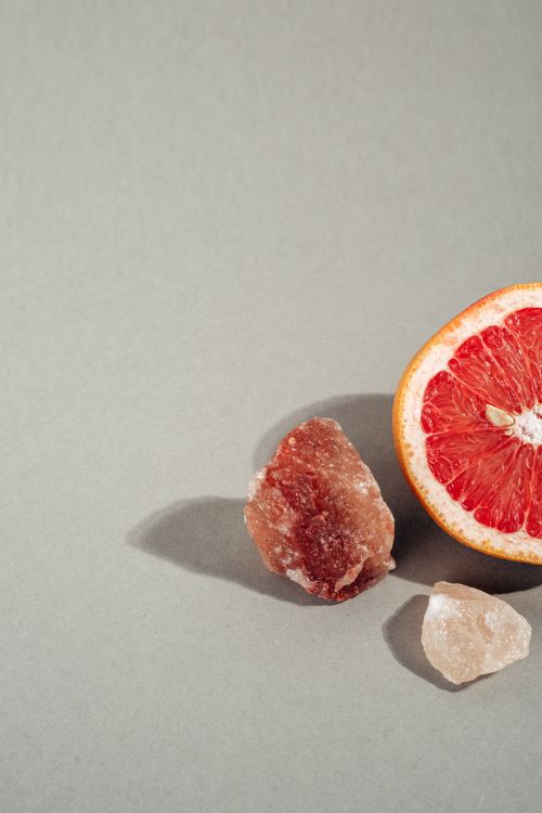 Free Minimalist composition of a grapefruit half and Himalayan salt crystals on a neutral background. Stock Photo