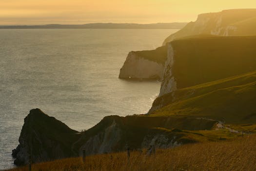Breathtaking view of the Jurassic Coast cliffs and ocean at sunset, showcasing natural beauty.