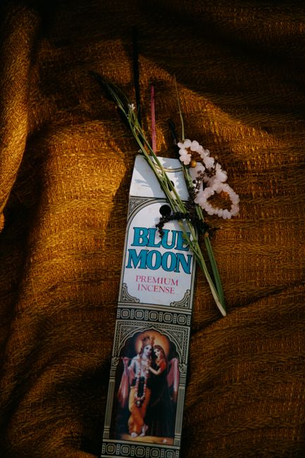 Colorful floral arrangement with Blue Moon incense on textured fabric. Tranquil, warm atmosphere.