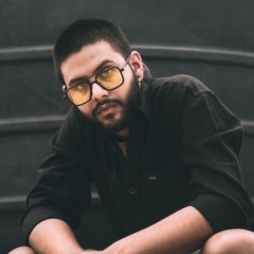 Free Portrait of a stylish young man with a beard and eyeglasses, posing confidently. Stock Photo