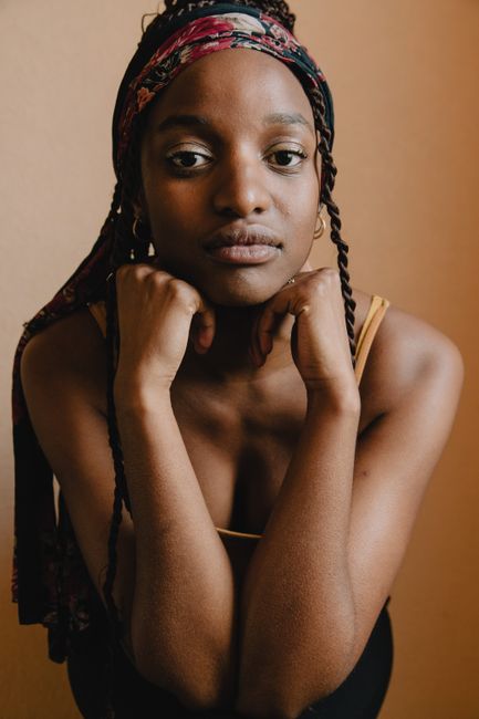 A thoughtful portrait of a woman in a headscarf against a warm background.