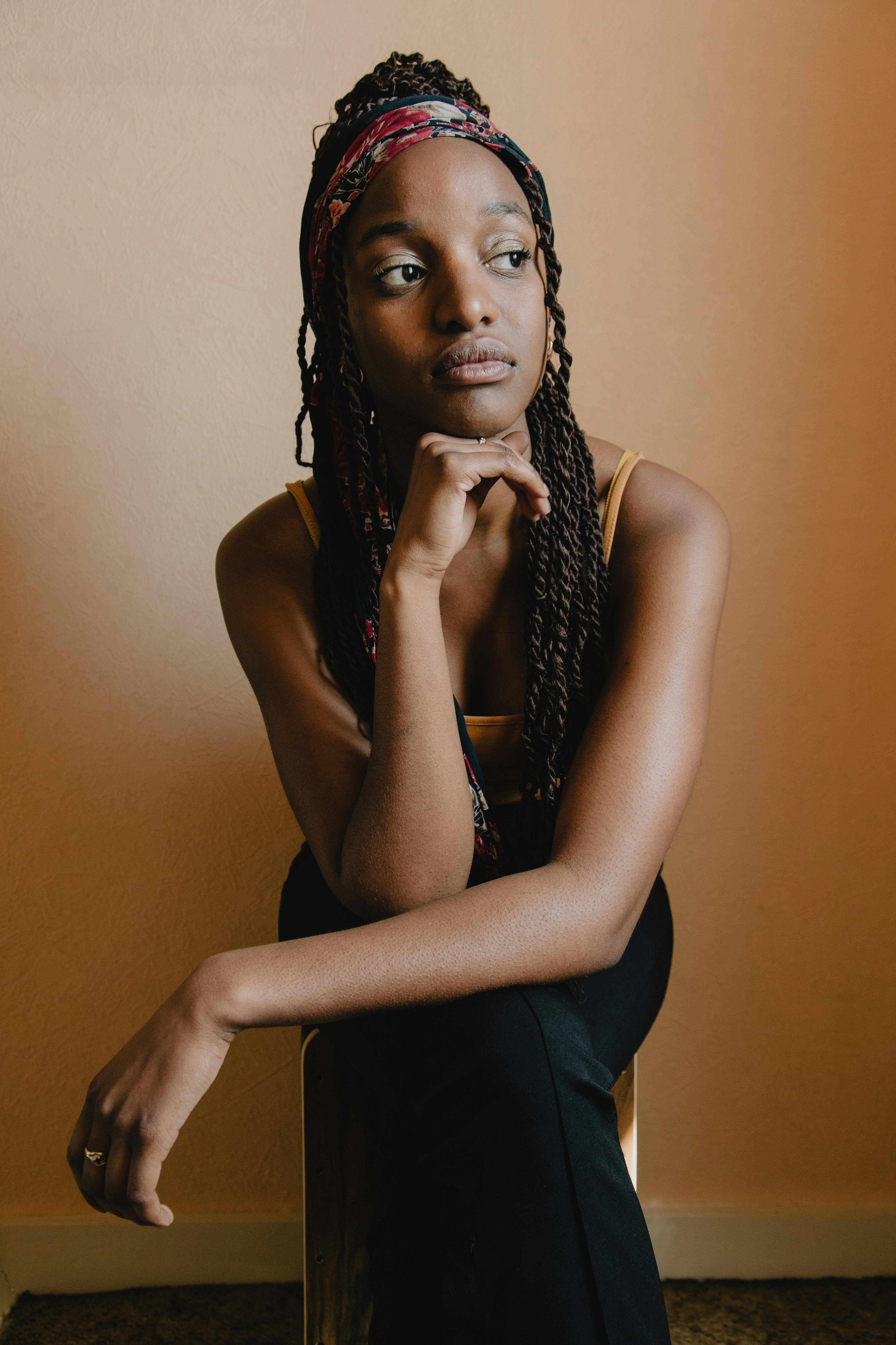 Portrait of a thoughtful woman posing indoors with hand on chin and braided hair.
