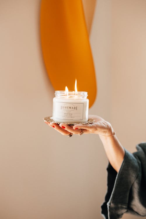 Person Holding Lighted White Candle in a Jar