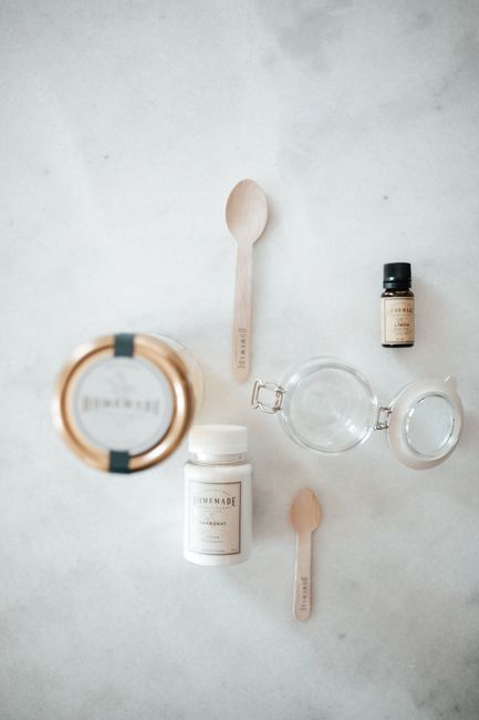 A glass jar of white, opaque lard with a spoon resting inside, next to a piece of pastry dough on a wooden board.