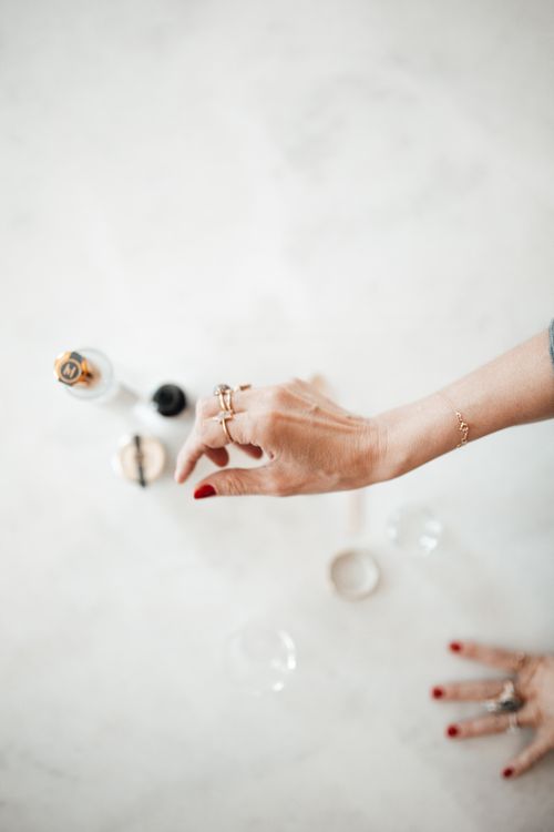 Free Close-up of a hand adorned with rings reaching for bottles on a marble surface, creating an elegant aesthetic. Stock Photo