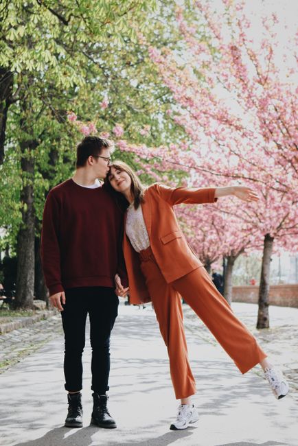 A joyful couple enjoying a spring day amidst cherry blossoms in a Budapest park.