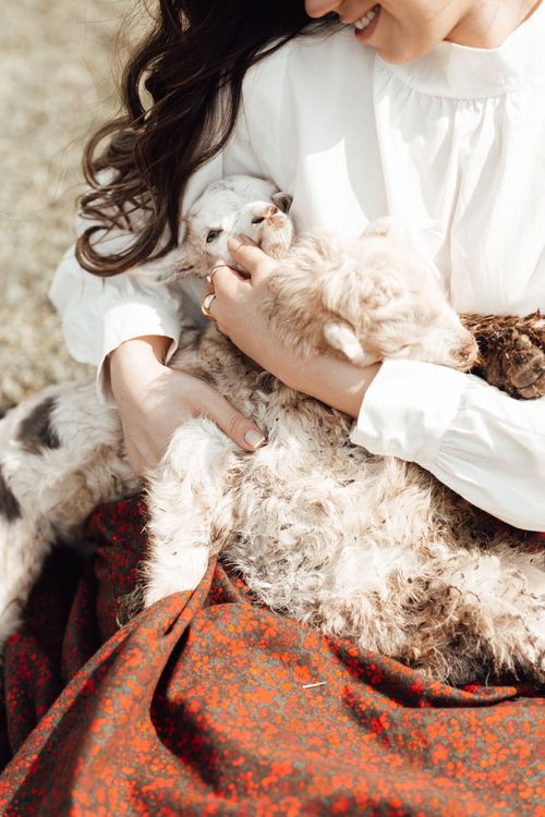 Free A woman gently cradles two baby goats outdoors, showcasing a tender moment. Stock Photo
