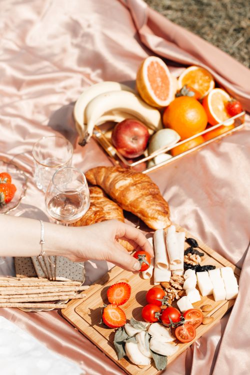 Free Vibrant picnic setup with fresh fruits, croissants, and cheese on a blanket. Stock Photo