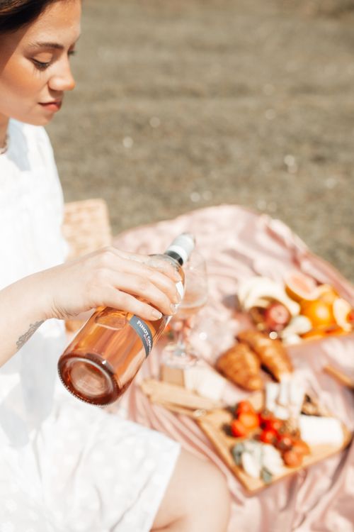 Free Woman pouring wine at a picnic with gourmet food selection outdoors. Stock Photo