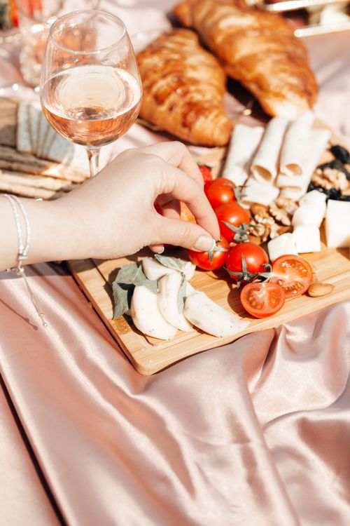 Free A stylish outdoor picnic setup with wine, cheese, fruits, and croissants in sunlight. Stock Photo