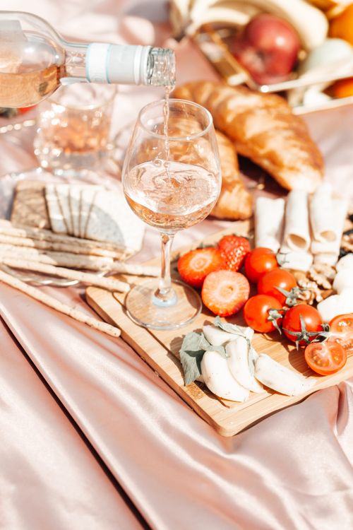 Free A chic outdoor picnic featuring wine, fresh fruits, and cheese on a sunny day. Stock Photo