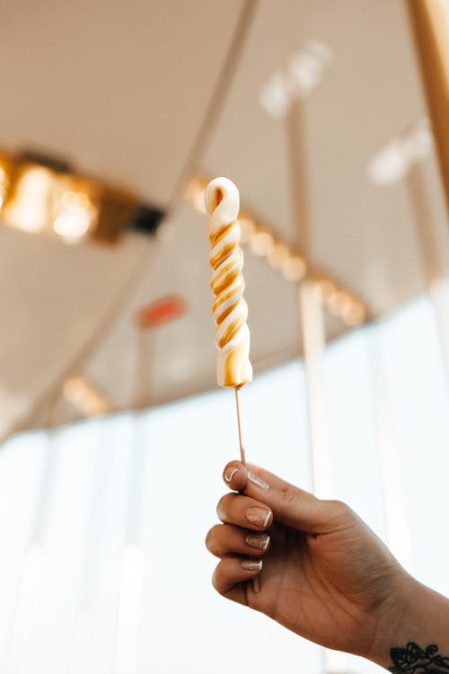 Person Holding White and Yellow Lollipop