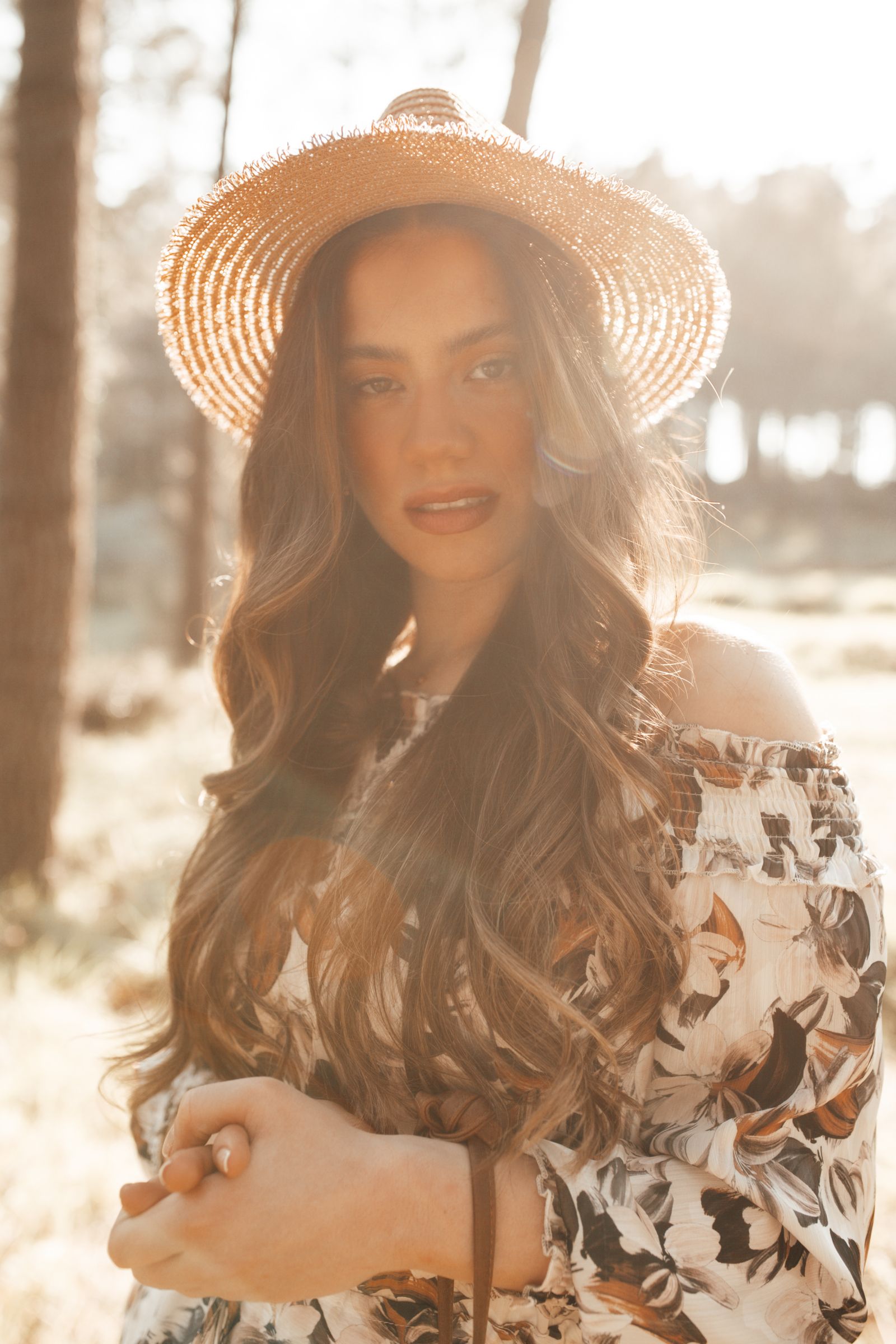 Amara Reyes, dharma and Ayurvedic living teacher, in warm golden light wearing a straw hat