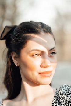Graceful portrait of a woman with sunlight and soft-focus background outdoors.