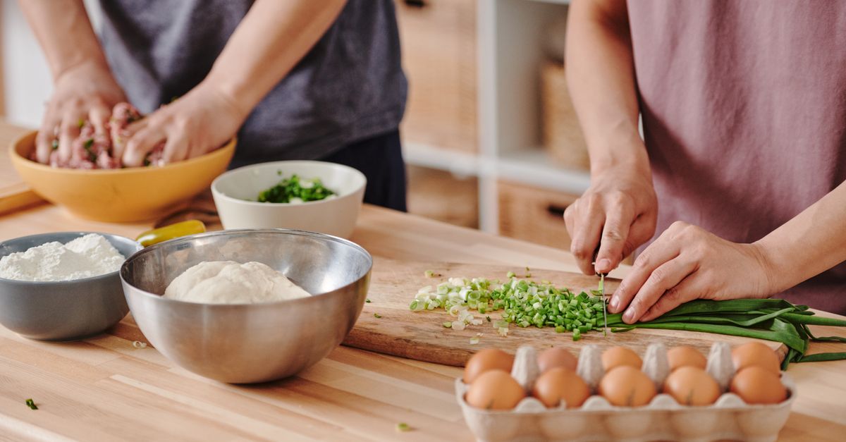 A messy kitchen counter with spilled flour, a half-chopped onion, and a handwritten recipe card