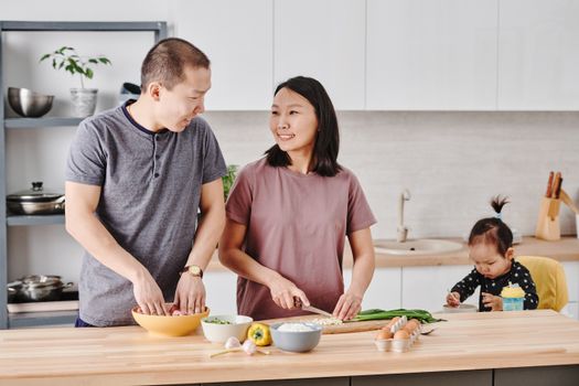 Asian family enjoying cooking together in a modern kitchen, fostering togetherness and love.