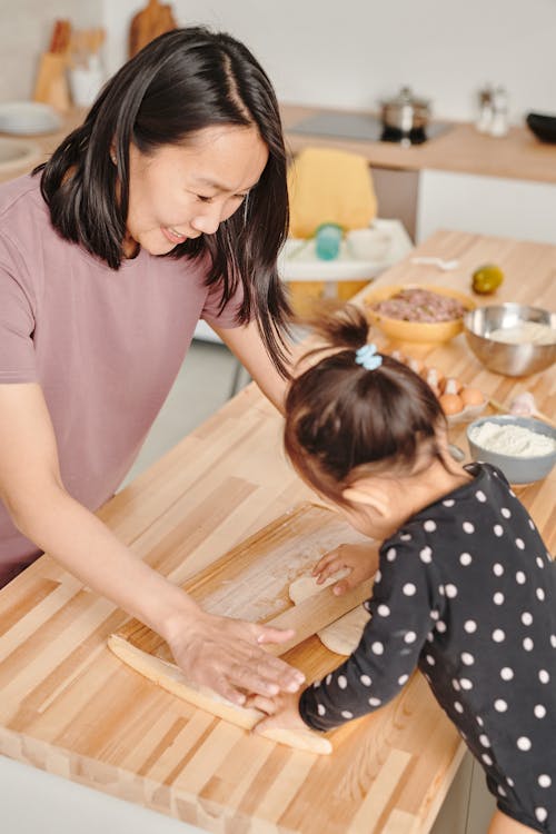 Woman Rolling A Dough With Her Daughter