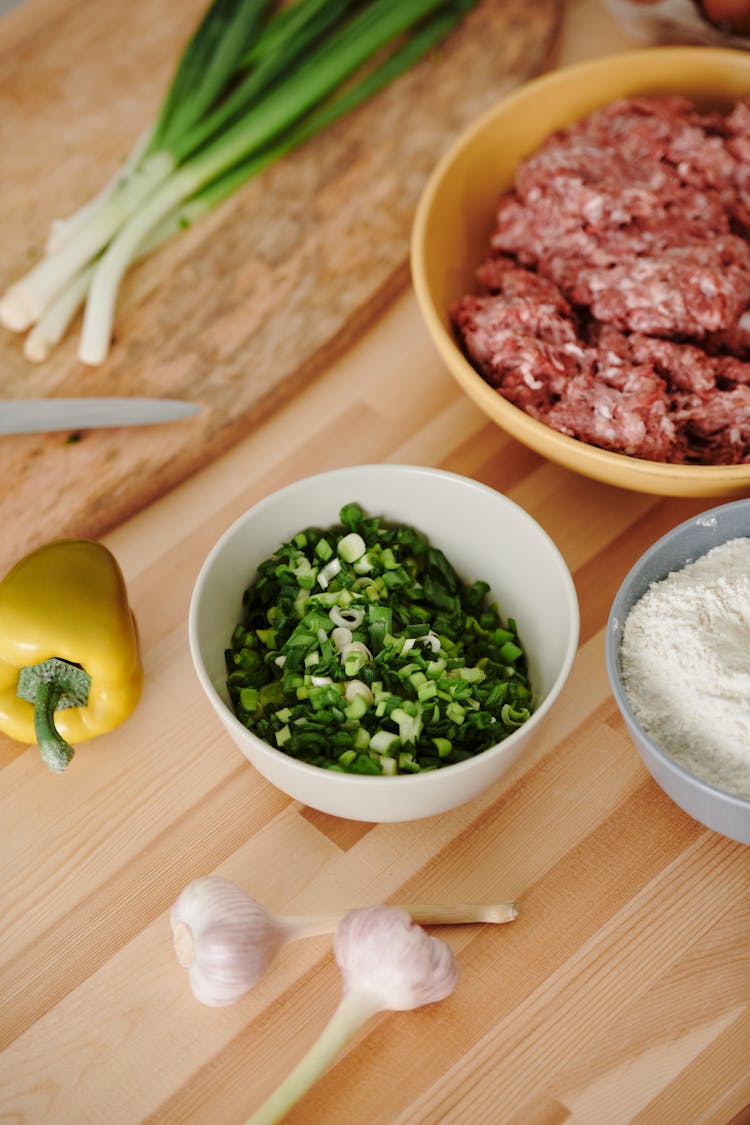 A Bowl Of Chopped Scallions Near A Bowl Of Minced Meat