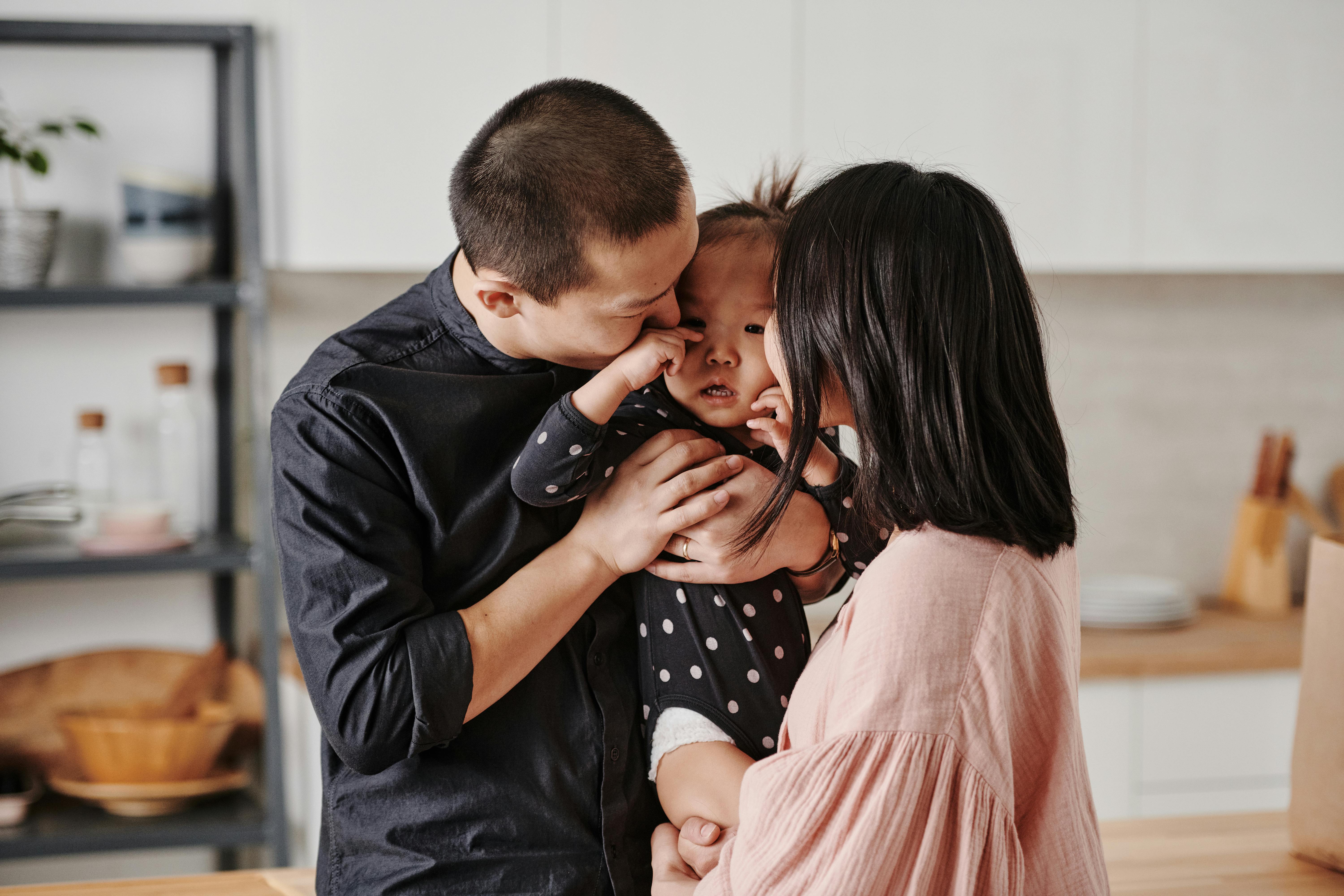 photo of a father and mother kissing their daughter