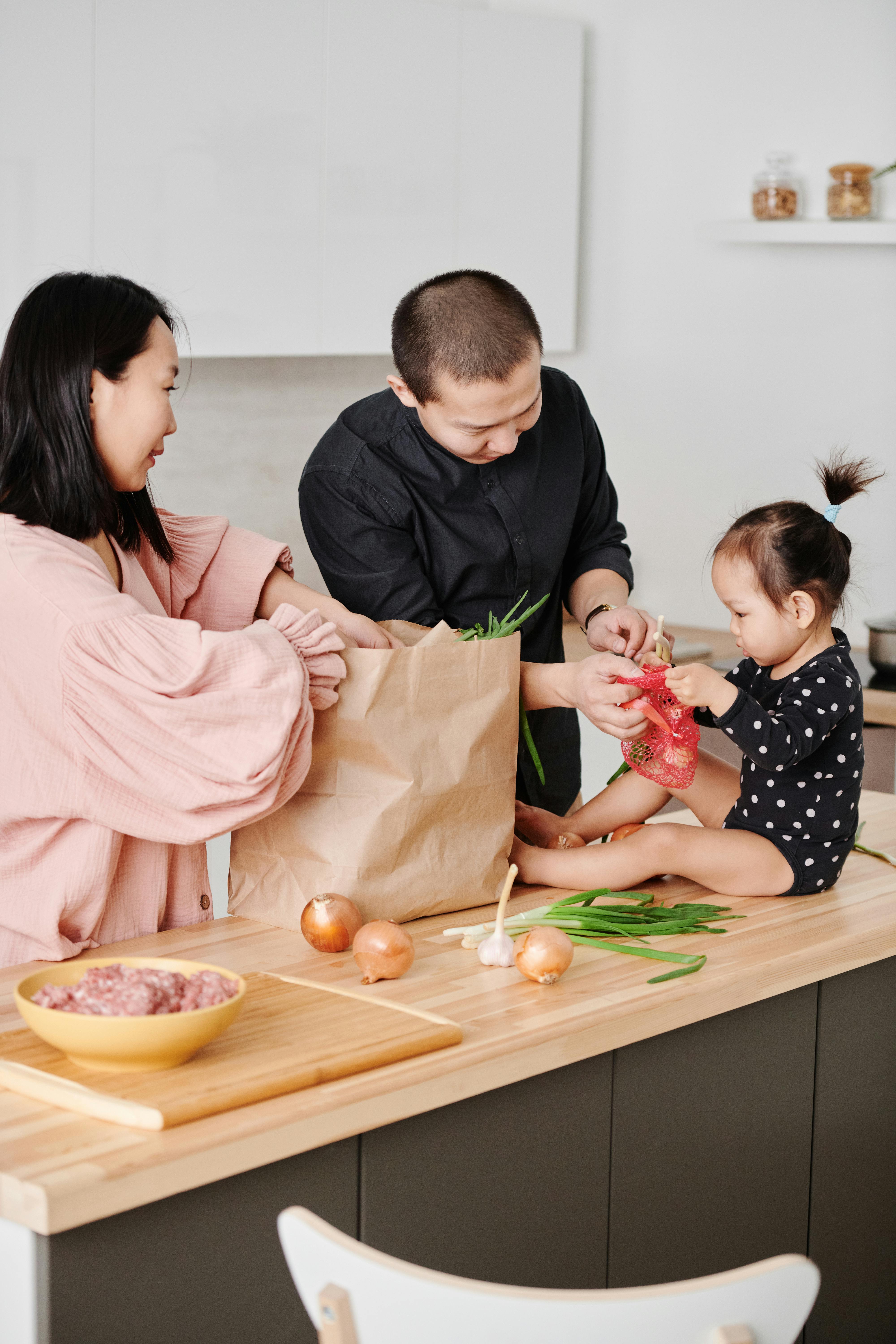 a family unpacking the groceries together from a paper bag