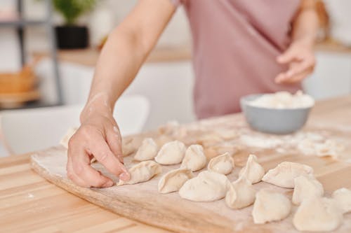 Person Holding White Dough on Wooden Tray